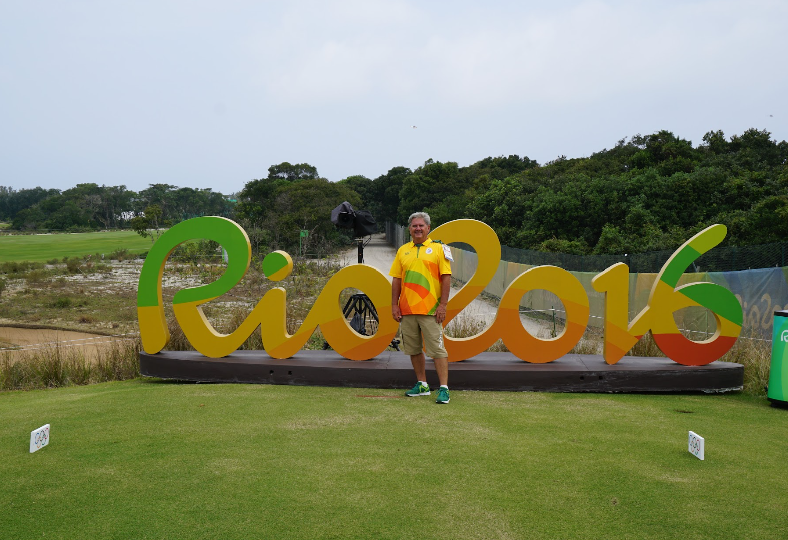 David Doguet standing on a golf course in front of a large sign that reads 'Rio 2016'.